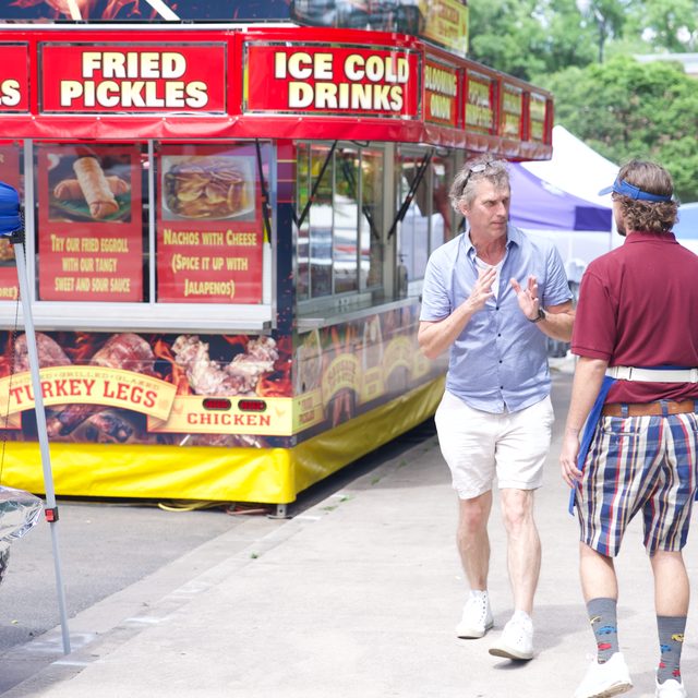 David walking a scene with an actor past a food truck at the street fair
