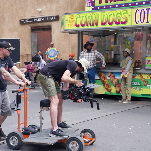 The dolly crew tracks a shot past the corn-dog stand