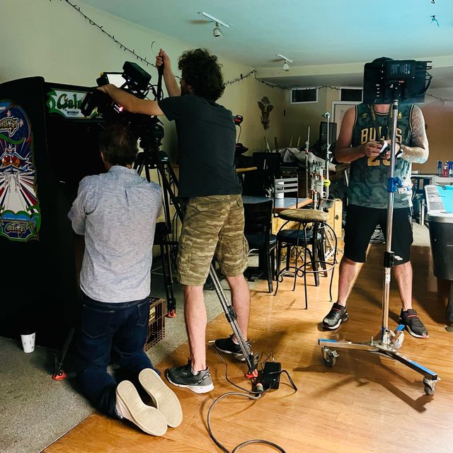 David kneels beside the camera at the Galaga machine