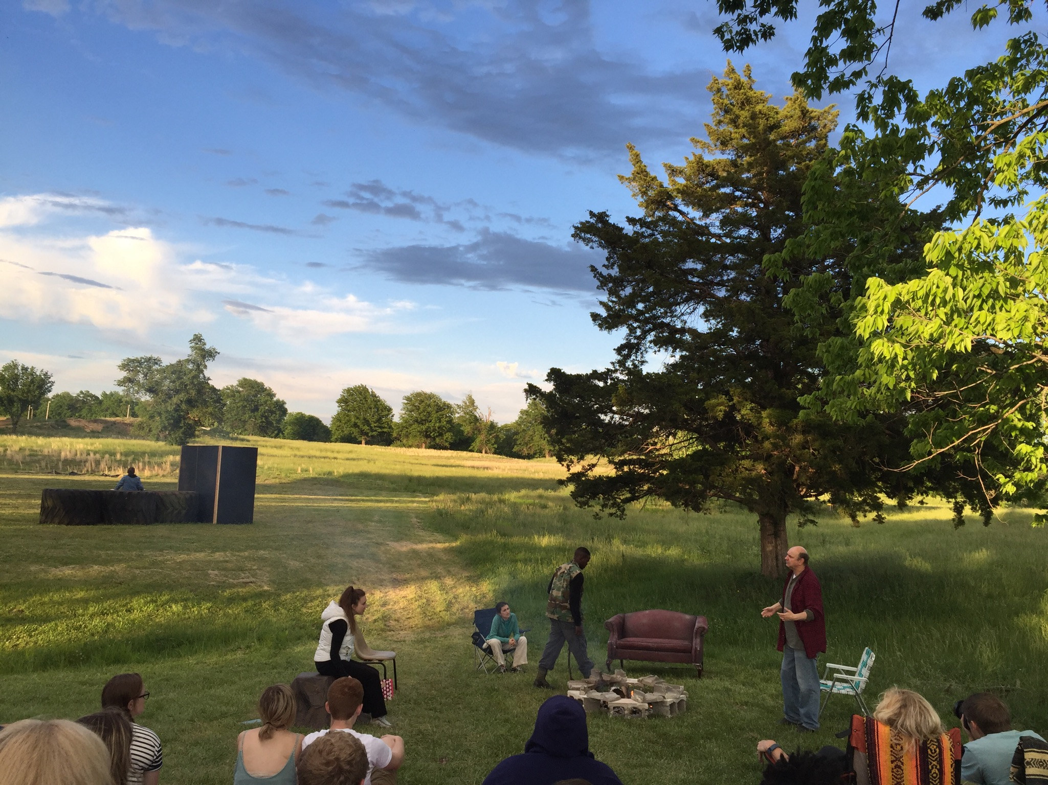 Act one: actors around a campfire in an open field at golden hour
